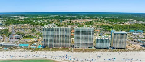 Un complejo hotelero costero con múltiples edificios de gran altura, una playa y una vista despejada del océano.