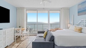 A hotel room with a balcony, a bed, a desk, and a TV. - Cast a Waves 512–Gulf Views–Sleeps 2 (Panama City Beach)
