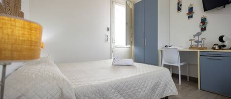 A bedroom with a bed, a desk, a chair, and a wardrobe.