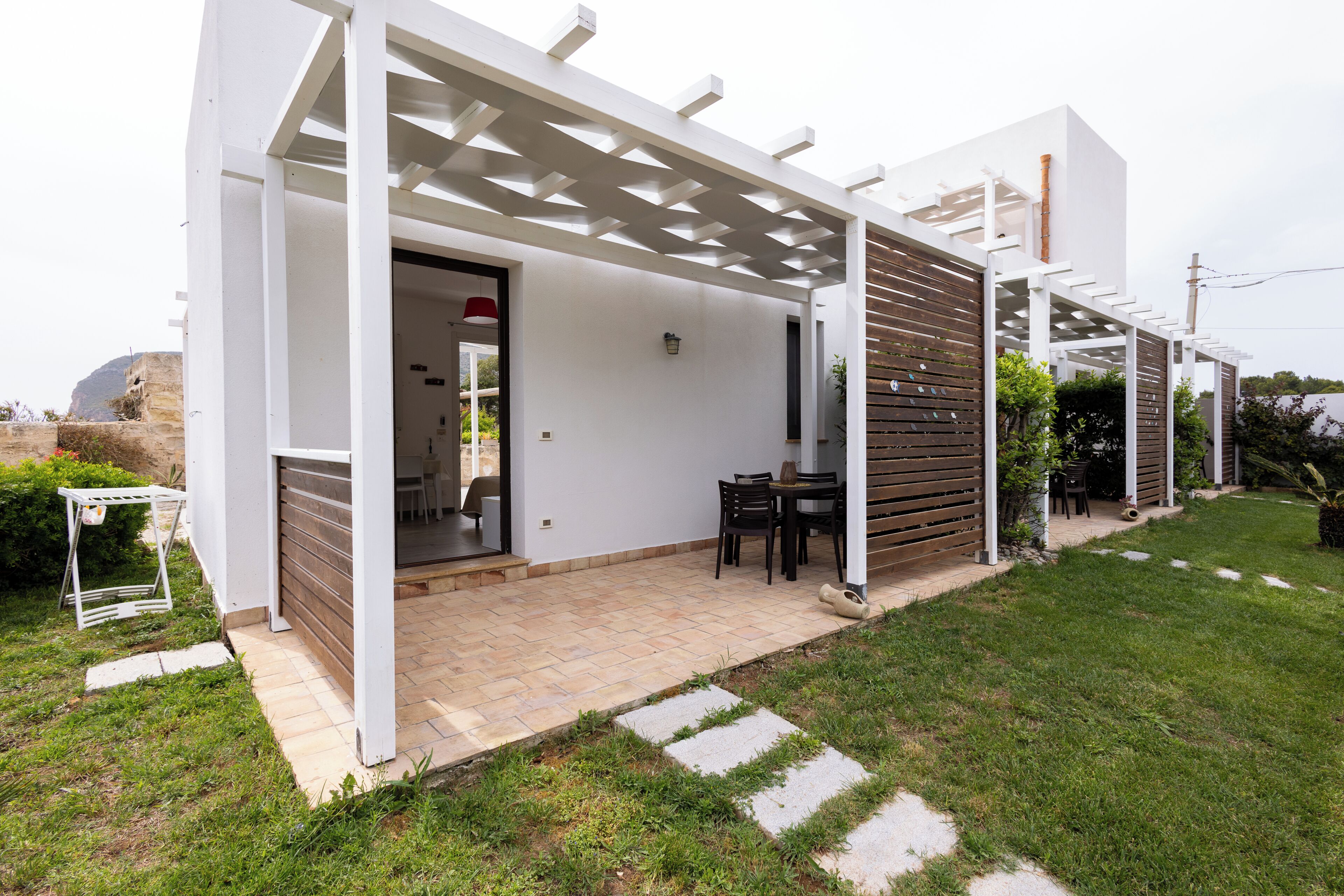A modern patio with a pergola, a table with chairs, and a small garden area.