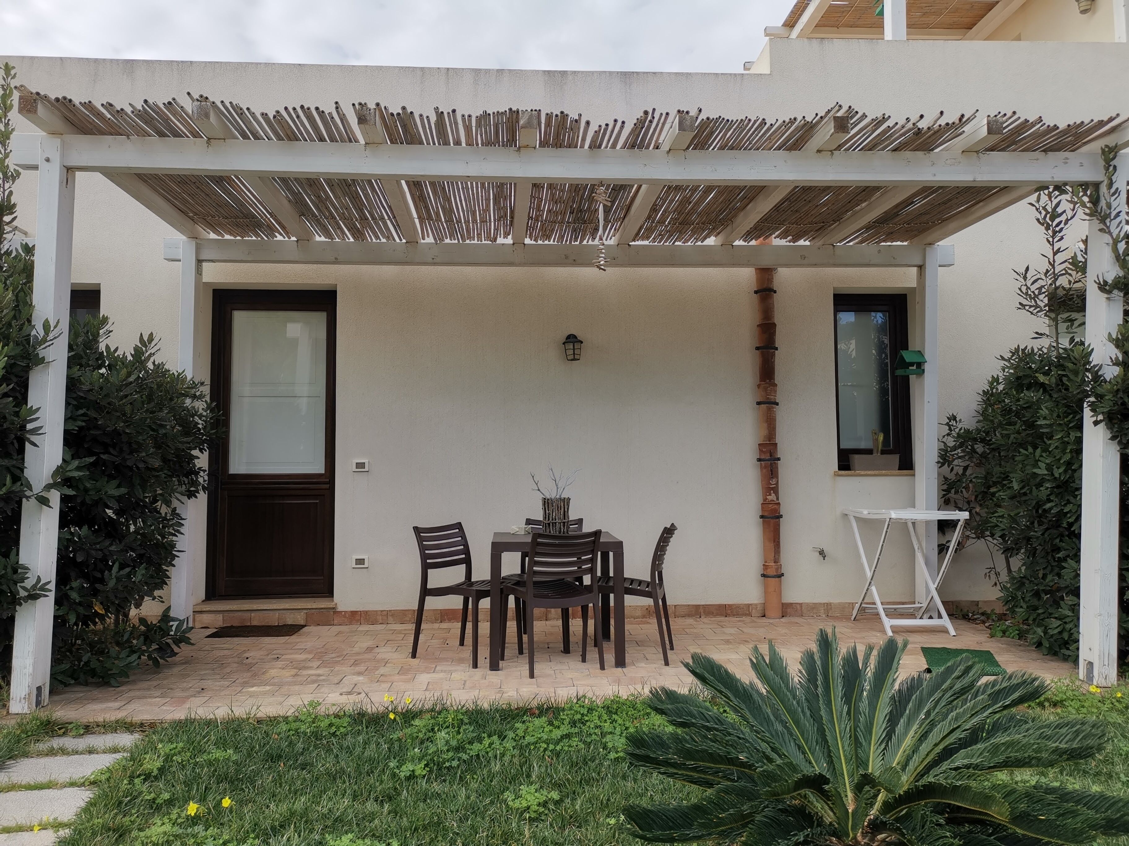 Un patio techado con una mesa, sillas, una puerta y una ventana.