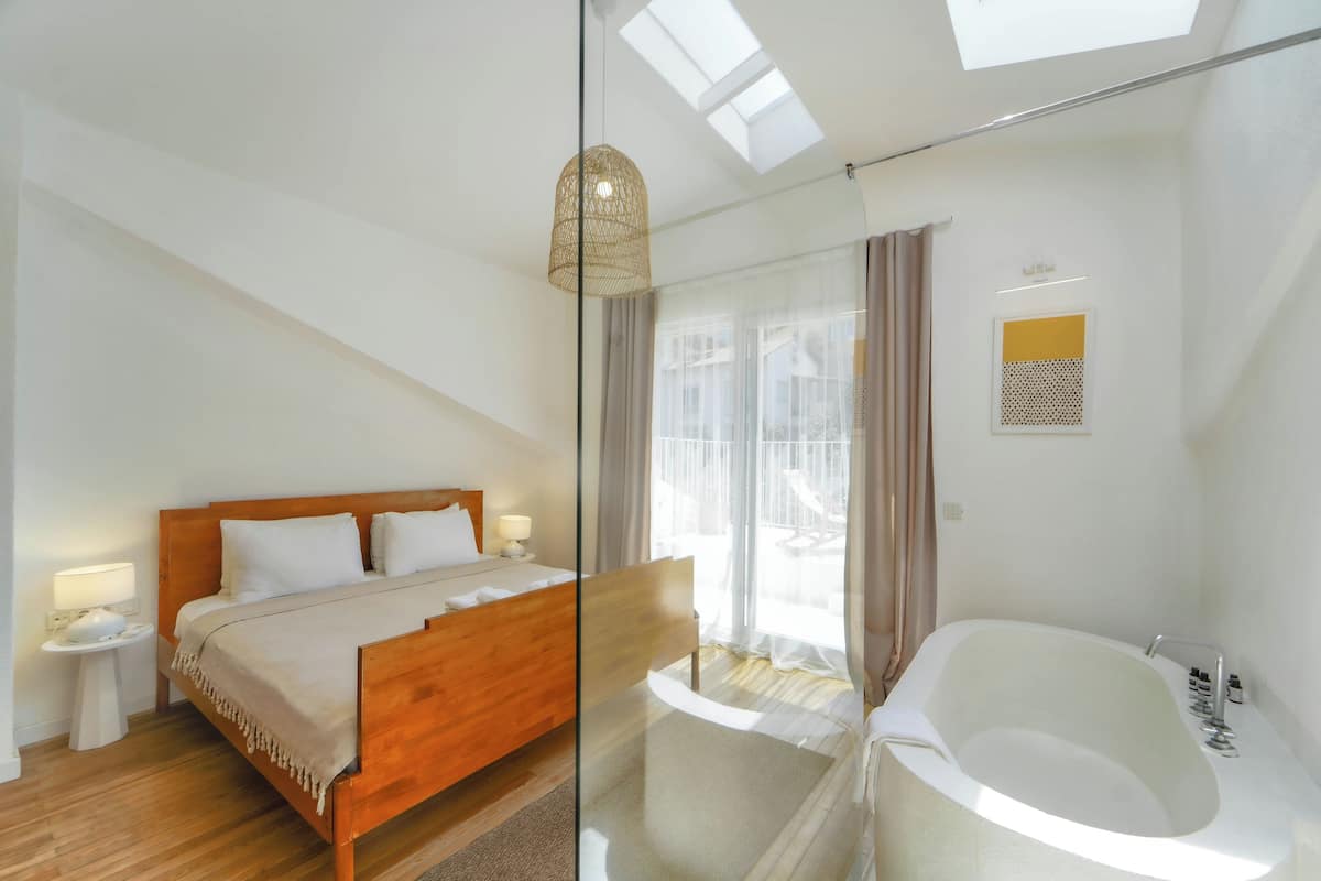 A modern bedroom with a wooden bed, a glass shower enclosure, and a skylight.