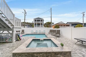 A swimming pool with a hot tub, a covered seating area, and a view of neighboring houses. - Just Coasting - Saltwater Pool, 5 Bedrooms, Across Street to Beach (North Myrtle Beach)