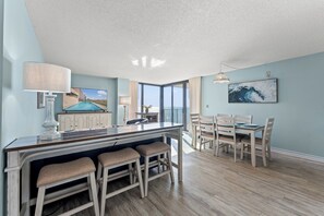 A spacious kitchen with a large island, bar stools, and a view of the ocean.