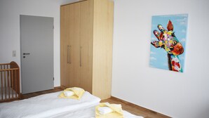 Une chambre avec deux lits, une armoire en bois et un tableau représentant une girafe accroché au mur.