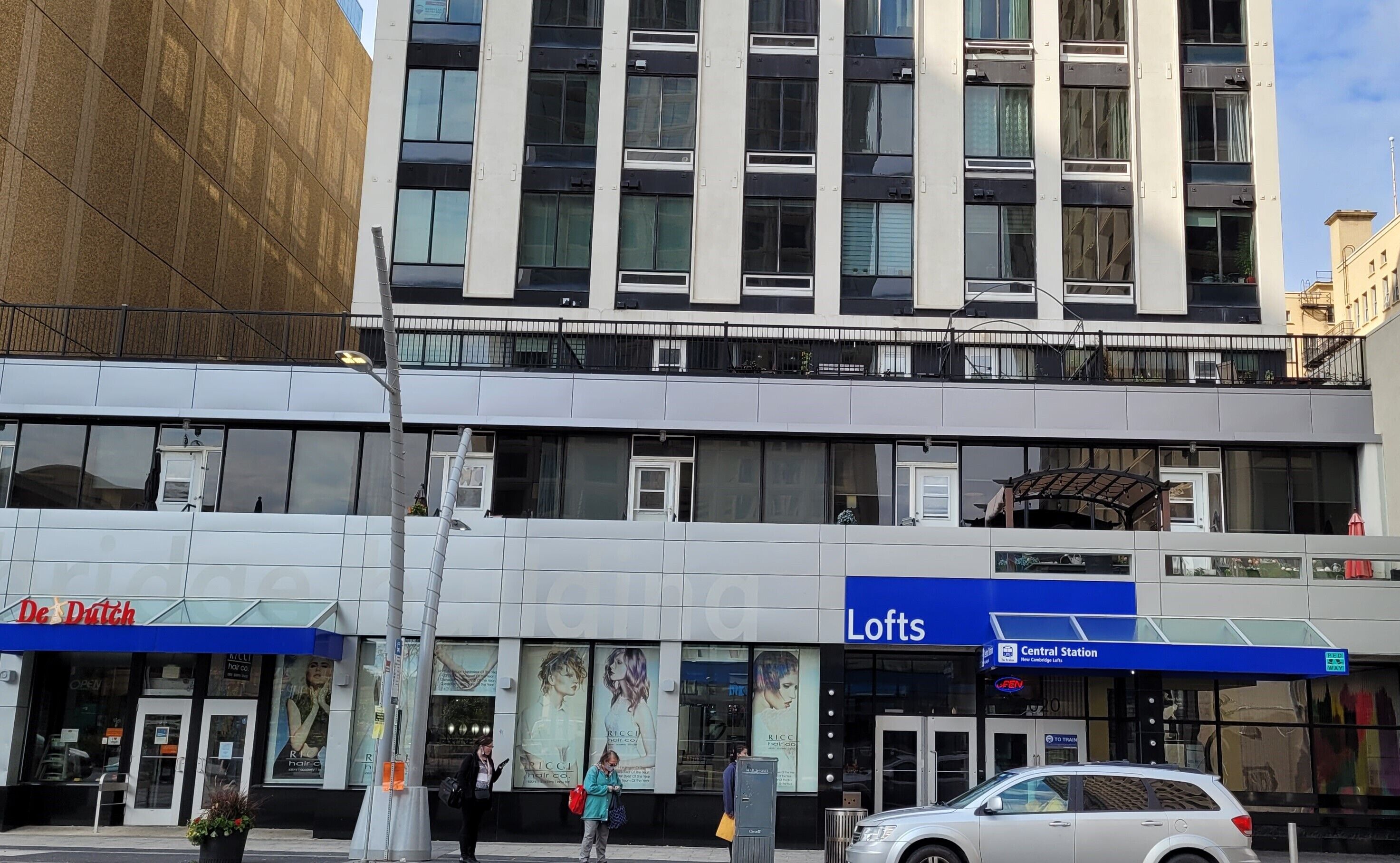 A multi-story building with a modern facade, featuring a hair salon named 'De Dutch' and a 'Lofts' retail space.