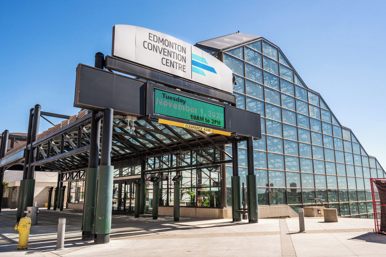 The Edmonton Convention Centre with a large glass building, a covered entrance, and a digital sign displaying the date and time.