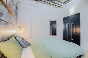 Une chambre à coucher comprenant un lit, une lampe fixée au mur, une fenêtre et une armoire.