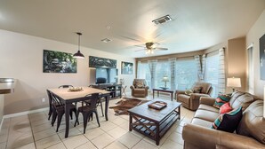 A spacious living room with a dining area, leather sofas, a coffee table, and a ceiling fan. - Waterwheel Ww B202 2 Bedroom Condo by RedAwning (New Braunfels)