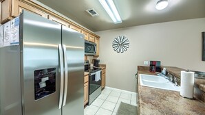 A modern kitchen with stainless steel appliances, a microwave, and a sink. - Waterwheel Ww B202 2 Bedroom Condo by RedAwning (New Braunfels)