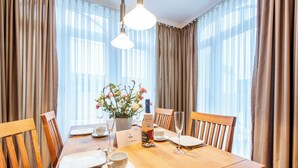 A dining table set for four with a vase of flowers, a bottle of wine, and a menu card. - Komfortabel. Zentral. Wellness. Residenz Bismarck, Whg. 1 Objekt-id: Hrb/01 (Westerland)