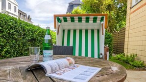 A round wooden table with a magazine, a glass of water, and a bottle of water. - Komfortabel. Zentral. Wellness. Residenz Bismarck, Whg. 1 Objekt-id: Hrb/01 (Westerland)