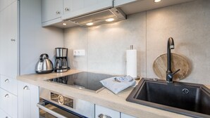 A modern kitchen with a stainless steel sink, a built-in stove, and a coffee maker. - Modern. Ruhig. Südterrasse (Westerland)