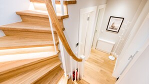 Eine Holztreppe führt zu einem Raum mit einer weißen Tür und einem gerahmten Bild an der Wand.