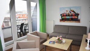 Ett modernt vardagsrum med en soffa, fåtöljer, ett soffbord och en tavla på väggen.