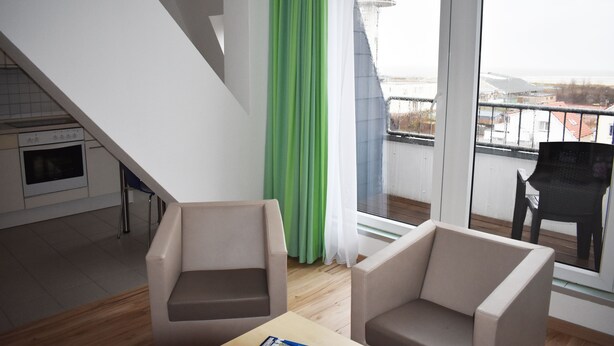Ett modernt kök med en inbyggd ugn och en matplats med två stolar och ett bord.