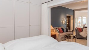Ett sovrum med en stor garderob, en soffa och en fåtölj i ett vardagsrum.