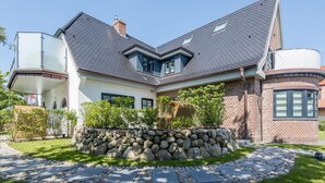 Ett modernt hus med en grund av sten, ett sluttande tak och en inglasad veranda.