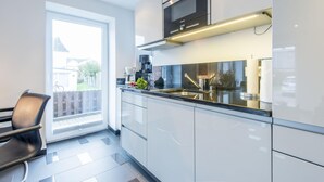 A modern kitchen with white cabinets, a stainless steel sink, and a microwave. - Hell. Entspannend. Komfortabel (Westerland)