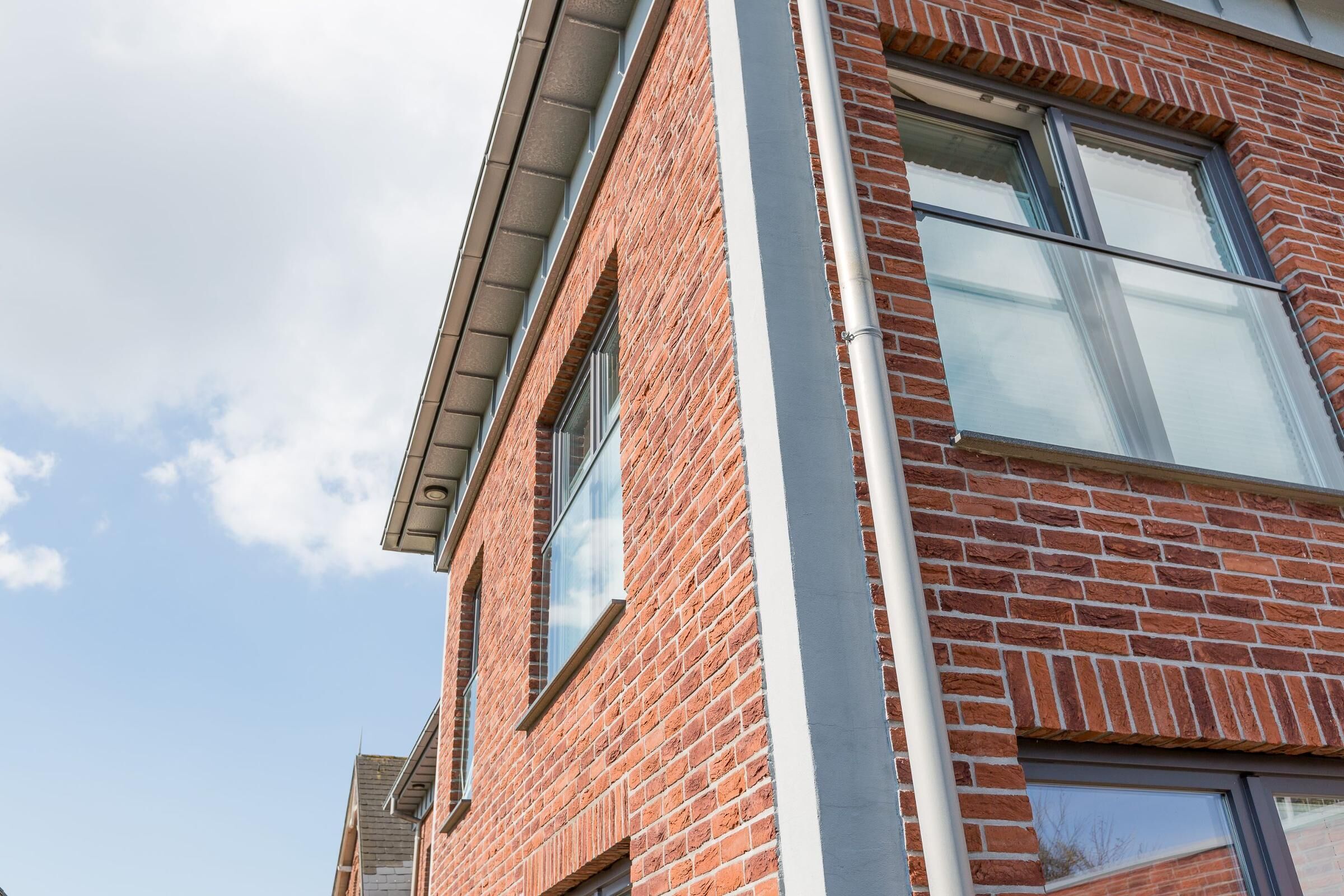 Een gebouw van rode baksteen met grote ramen en een duidelijke dakgoot.