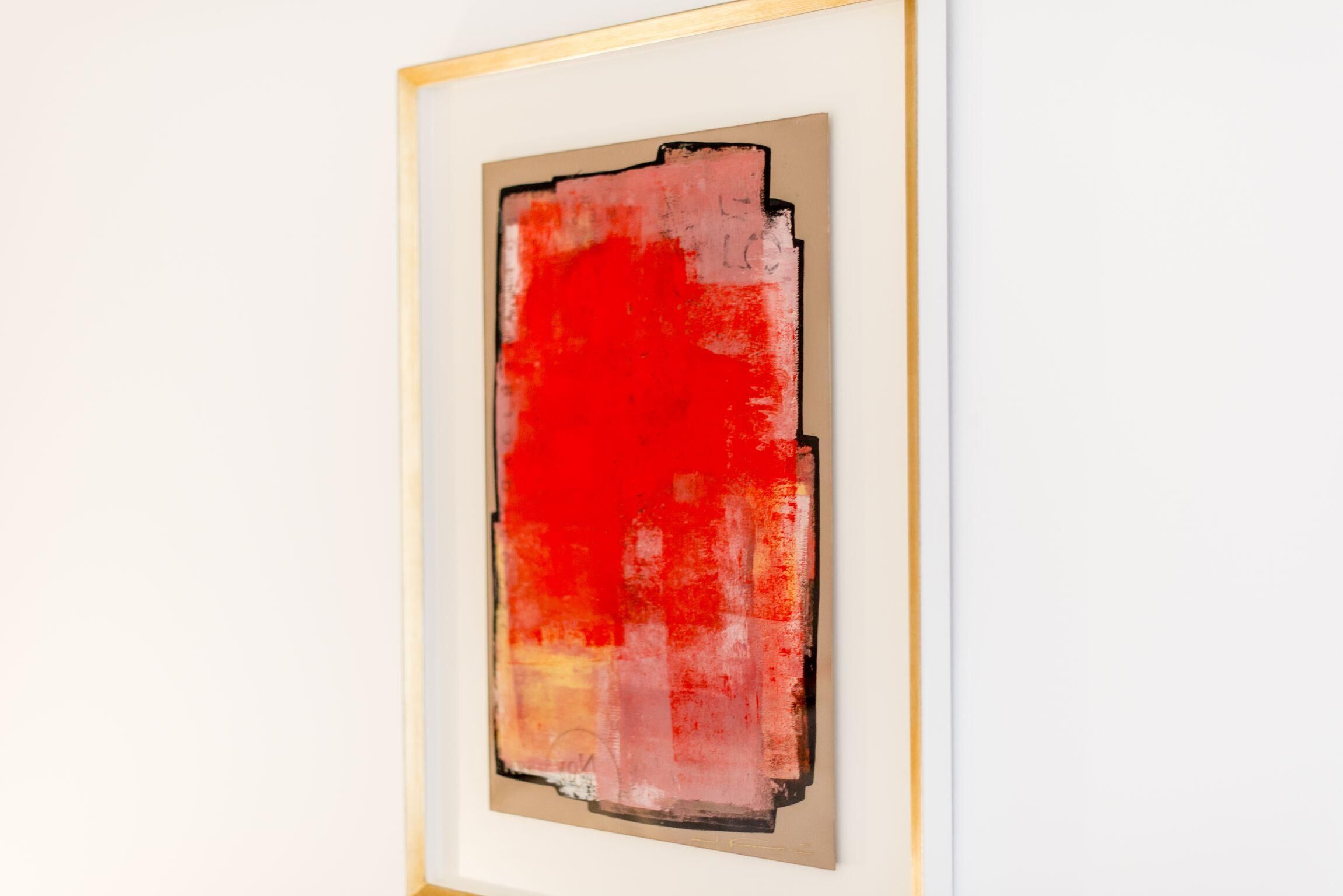 Une peinture abstraite encadrée aux couleurs rouge et beige.