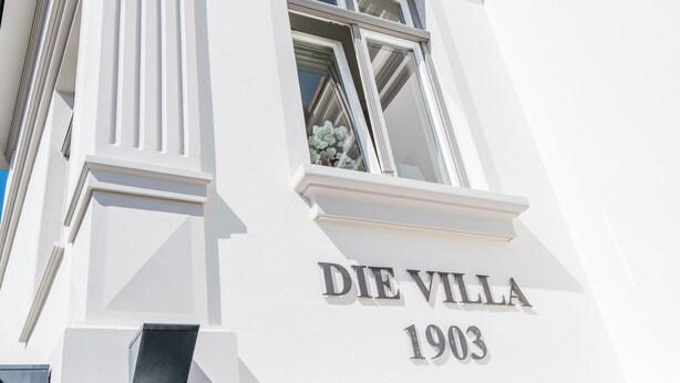 Un bâtiment dont la façade porte l’inscription « DIE VILLA 1903 ».