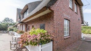 A brick building with a white picket fence and a planter with pink flowers.