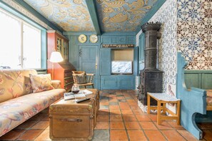 A room with a blue wall, a fireplace, a sofa, a wooden table, and a suitcase.