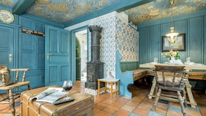 A room with a large blue door, a vintage suitcase, a wooden chair, a small table, and a fireplace.