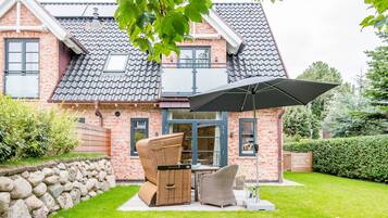 A brick house with a tiled roof, a stone wall, and a grassy lawn.