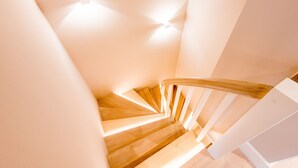 Een wenteltrap met houten treden en witte leuningen, die omhoog leidt in een modern interieur.