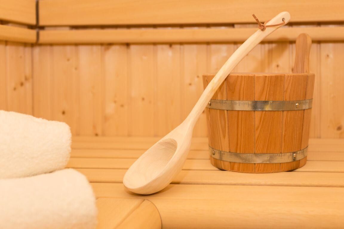 Una sauna de fusta amb un cub i una cullera de fusta.