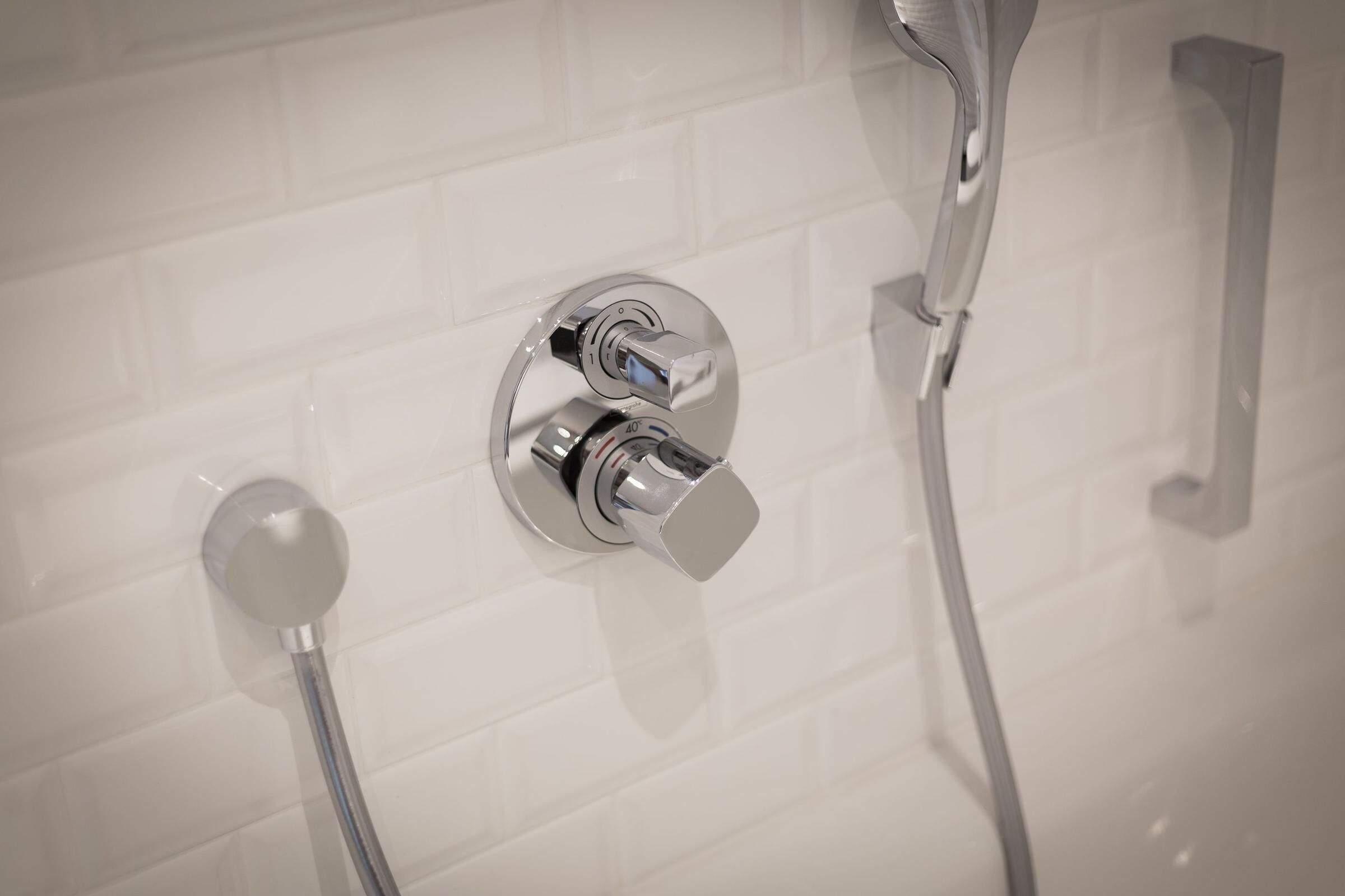 Ein modernes Badezimmer mit Duschkopf aus Chrom, Handbrause und am Wand montierter Armatur.
