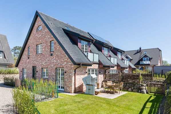 A large brick house with multiple gabled roofs and a well-maintained lawn.