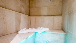 A corner of a bathroom with a white towel on a shelf and a blue-lit shower area. - Exquisit. Wellness. Balkon. Höög Hüs, Whg. 2A Objekt-id: Whw/02a (Westerland)