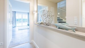 En moderne gang med indbygget bænk, en dekorativ koraldskulptur og udsigt til et rummeligt værelse med trappe.