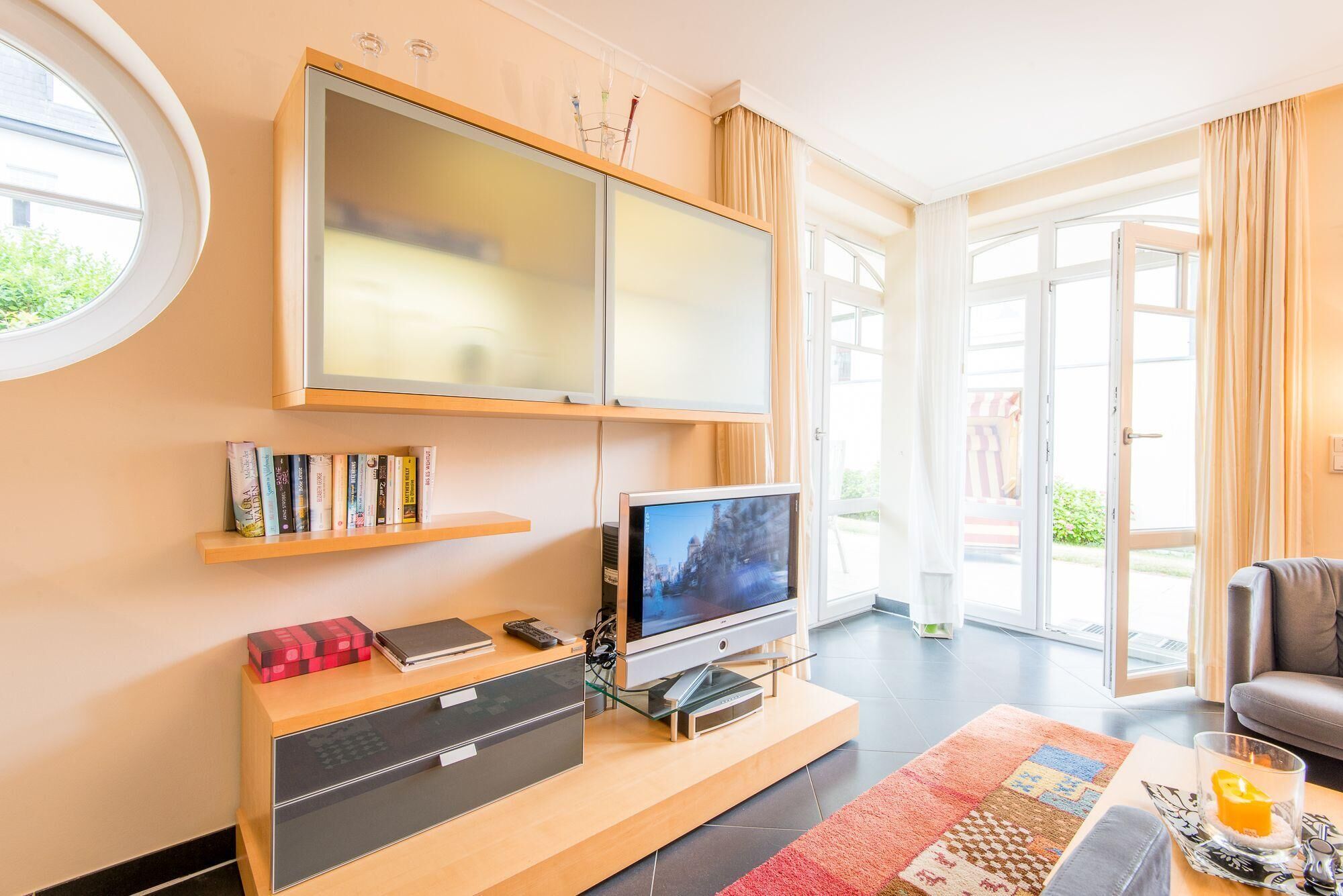 Un salon moderne doté d’un grand téléviseur à écran plat, d’un meuble de rangement en bois et d’une table basse en verre.