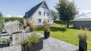 A modern house with a sloped roof, a paved driveway, and a well-maintained lawn. - Komfortabel. Ruhig. Gemütlich (Westerland)