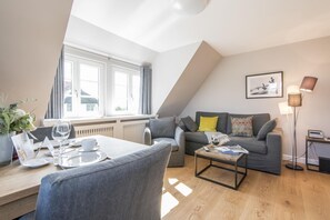 A modern living room with a dining area, a grey sofa with yellow pillows, a coffee table, and a floor lamp.