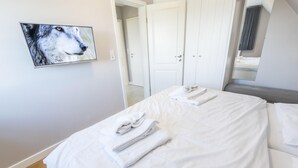 A hotel room with a bed, a TV mounted on the wall, and a door leading to another room. - Komfortabel. Ruhig. Gemütlich (Westerland)