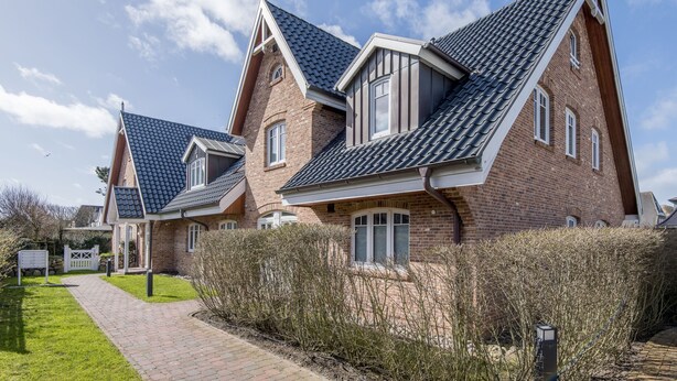 A row of brick houses with steeply pitched roofs and white window frames. - Strandnah. Ruhig. Komfortabel. Objekt-id: Hdr/04 (Westerland)