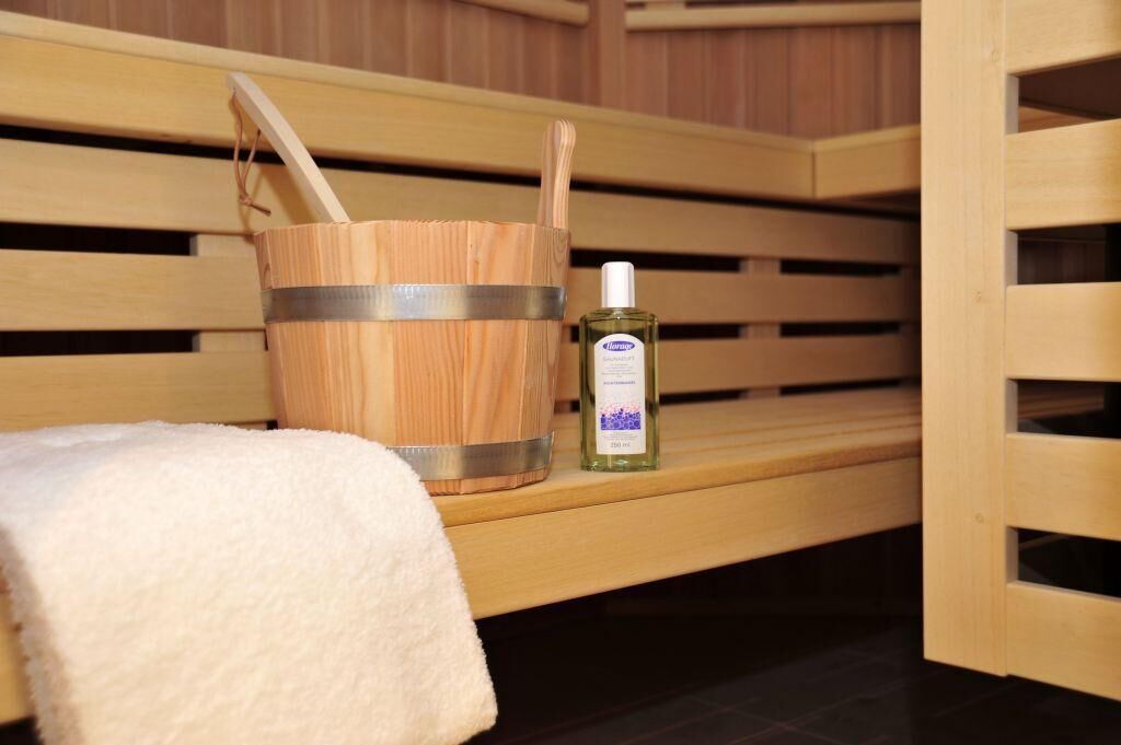 Een houten bank met een metalen emmer en een flesje lotion.
