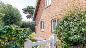 A brick house with a white gate, a small garden, and a stone wall. - Strandnah. Ruhig. Komfortabel. Objekt-id: Hdr/04 (Westerland)