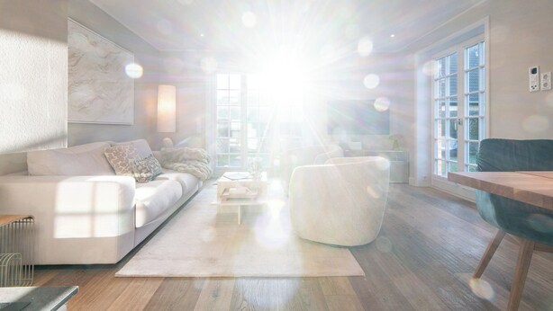 Ein modernes Wohnzimmer mit Sofa, Couchtisch und Essbereich mit Tisch und Stühlen.