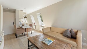 Una sala de estar moderna con una mesa de centro de madera, un sofá color beige y una zona de comedor con mesa y sillas.