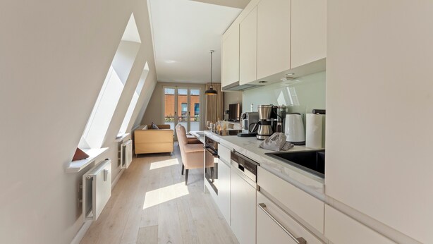 Una cocina moderna con lavavajillas incorporado, cafetera y vistas al exterior.