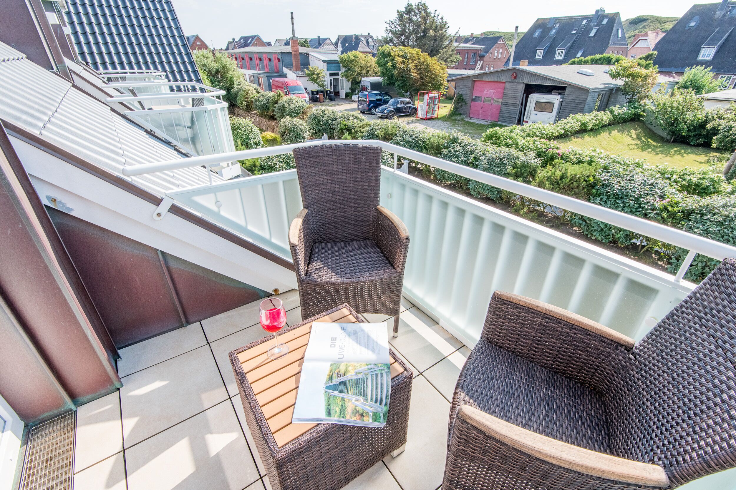 A balcony with wicker furniture, a glass table, and a magazine.