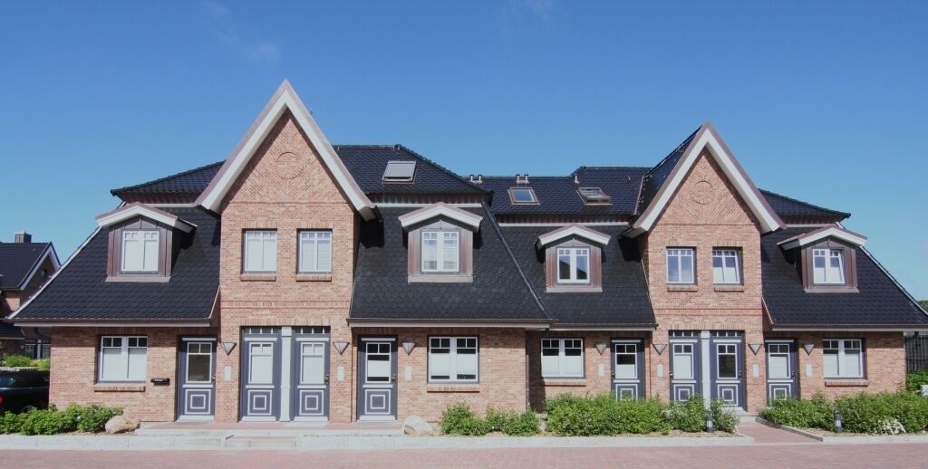 Une rangée de maisons de ville en briques, dotées de toits à pignon et de fenêtres en lucarne.