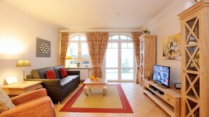 A living room with a sofa, a coffee table, a TV, and a wooden cabinet.