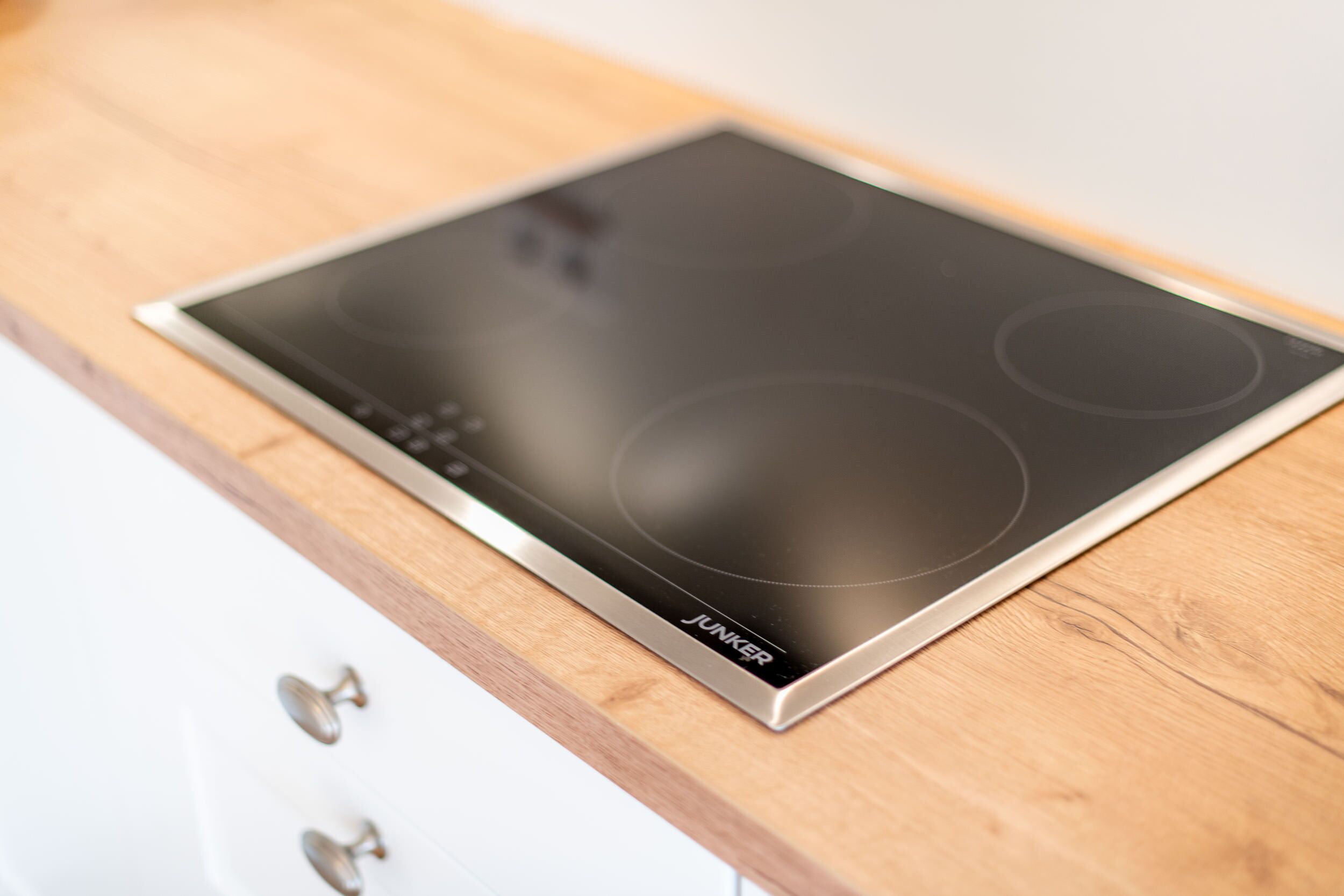 A modern kitchen with a stainless steel induction cooktop and a wooden countertop.